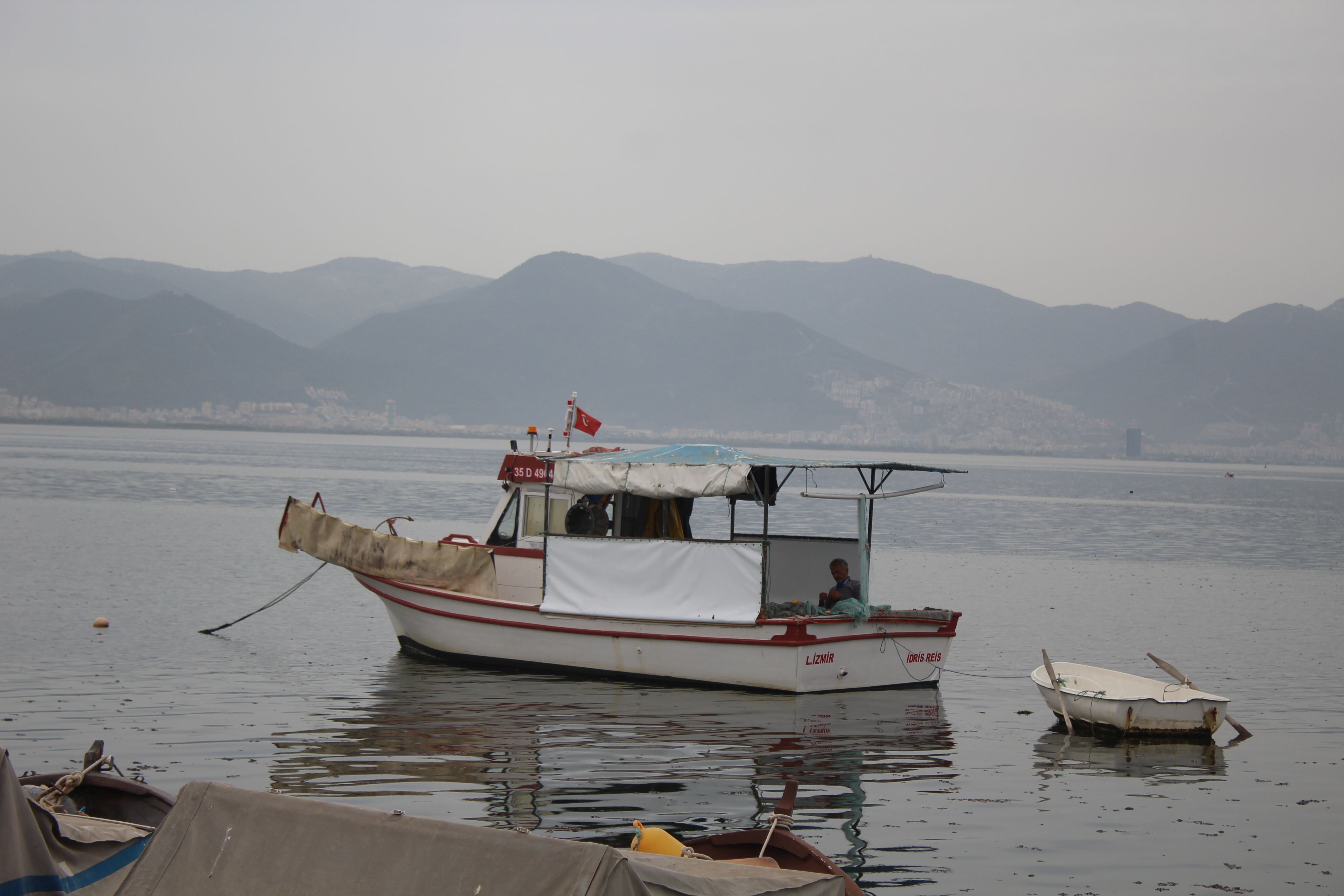 A serene scene of a boat floating on the Bosphorus with picturesque mountains in the background.