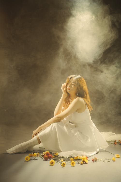 A woman sitting on the floor with flowers and smoke
