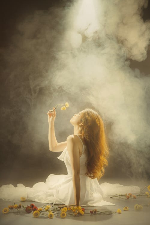 A woman in white dress sitting on the floor with smoke coming out of her