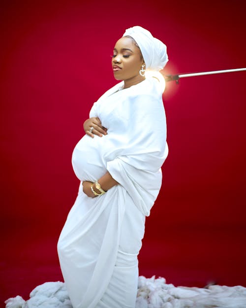 A pregnant woman in white is holding a stick