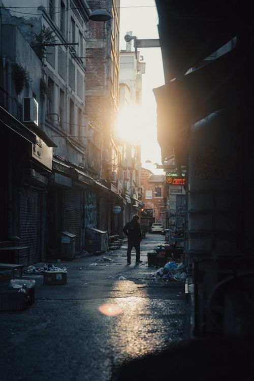 Free A solitary figure walks down a narrow city street in Istanbul at sunrise, capturing urban life. Stock Photo