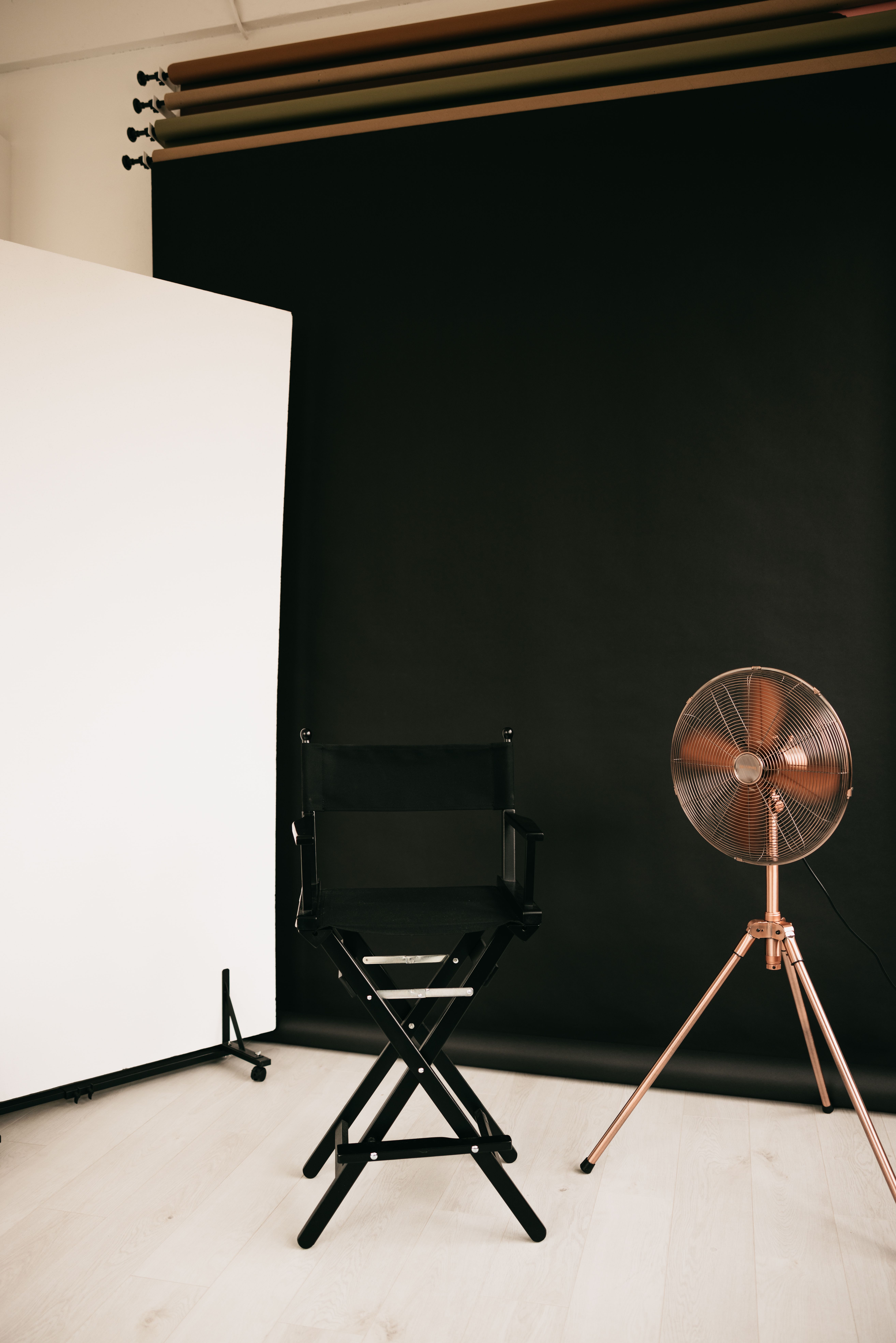 Stylish studio setup featuring a director's chair and vintage fan against a black backdrop.