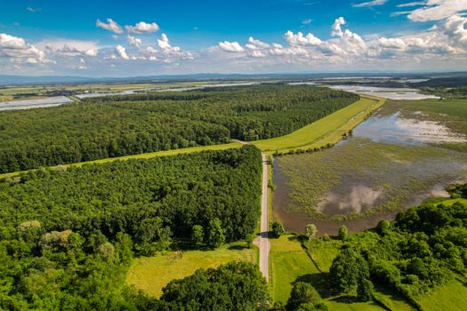 Stunning aerial view of Garešnica's lush countryside with forests and wetlands under a blue sky.
