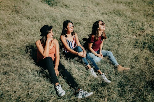 Three Women Sitting On Green Grass