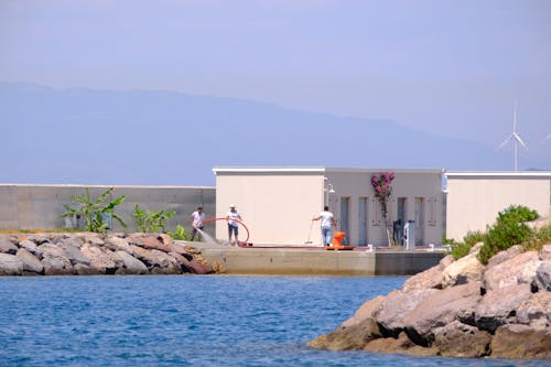 A man is standing on the shore near a building