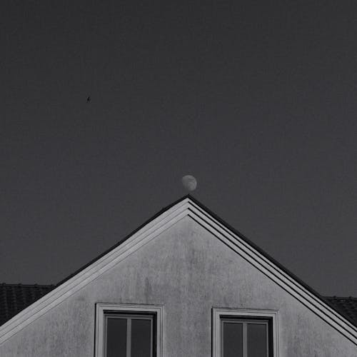 A black and white photo of a house with a moon