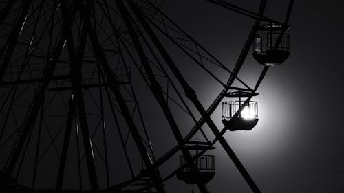 A ferris wheel in the dark with the moon in the background