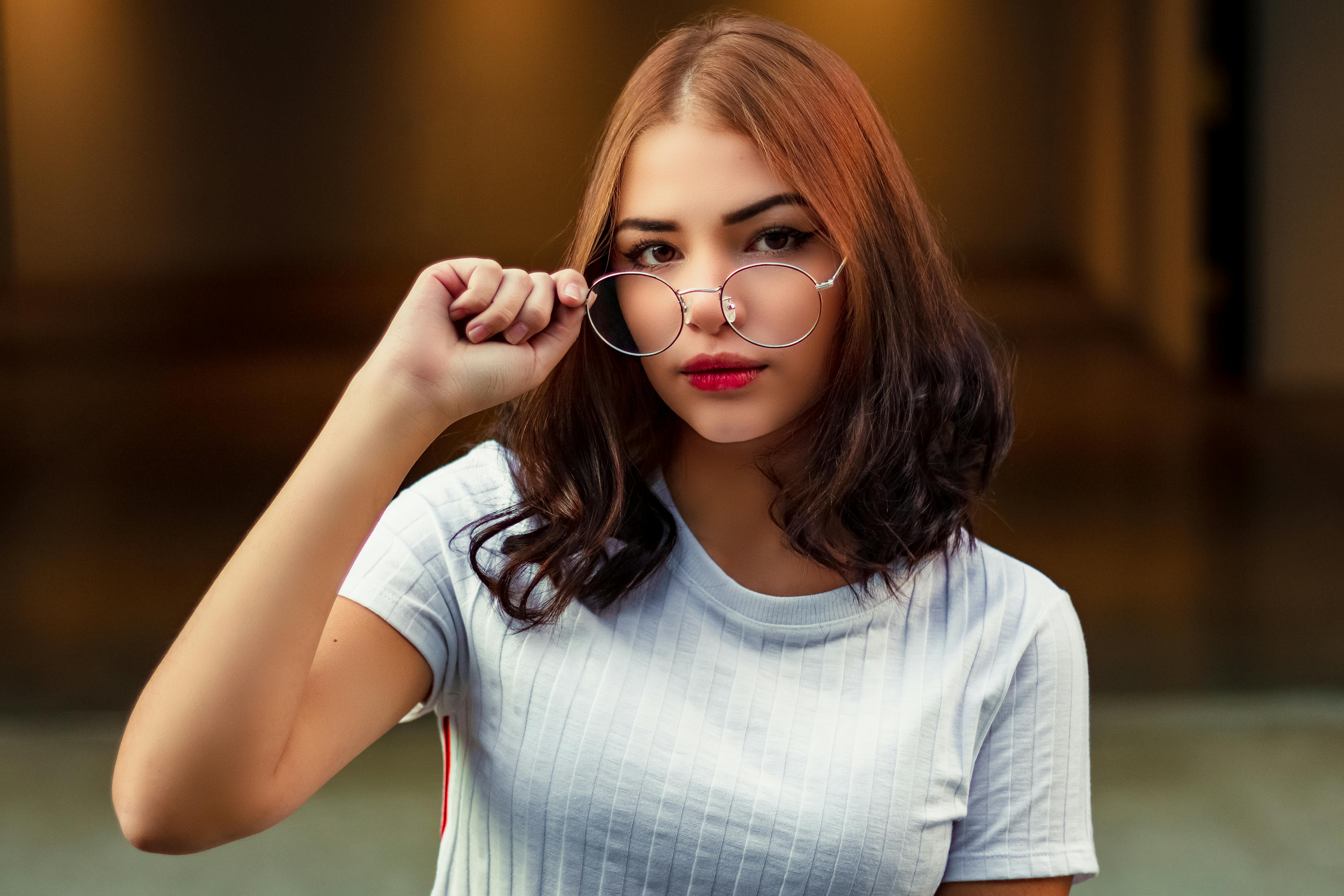 一位年轻时尚的女子在室内调整眼镜，散发着自信与优雅