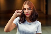 一位年轻时尚的女子在室内调整眼镜，散发着自信与优雅