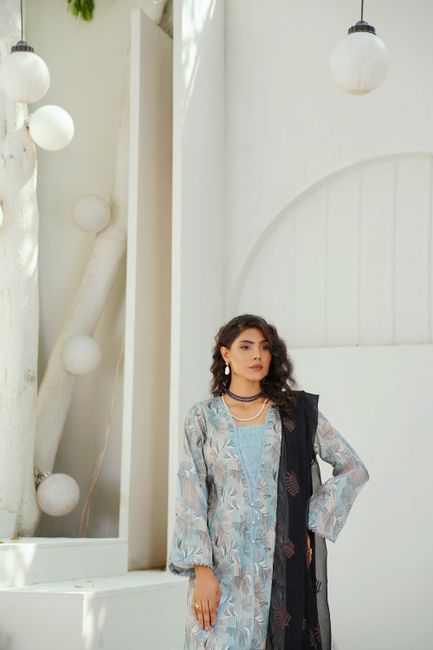 Fashionable woman poses outdoors in Lahore, wearing blue and black ensemble.