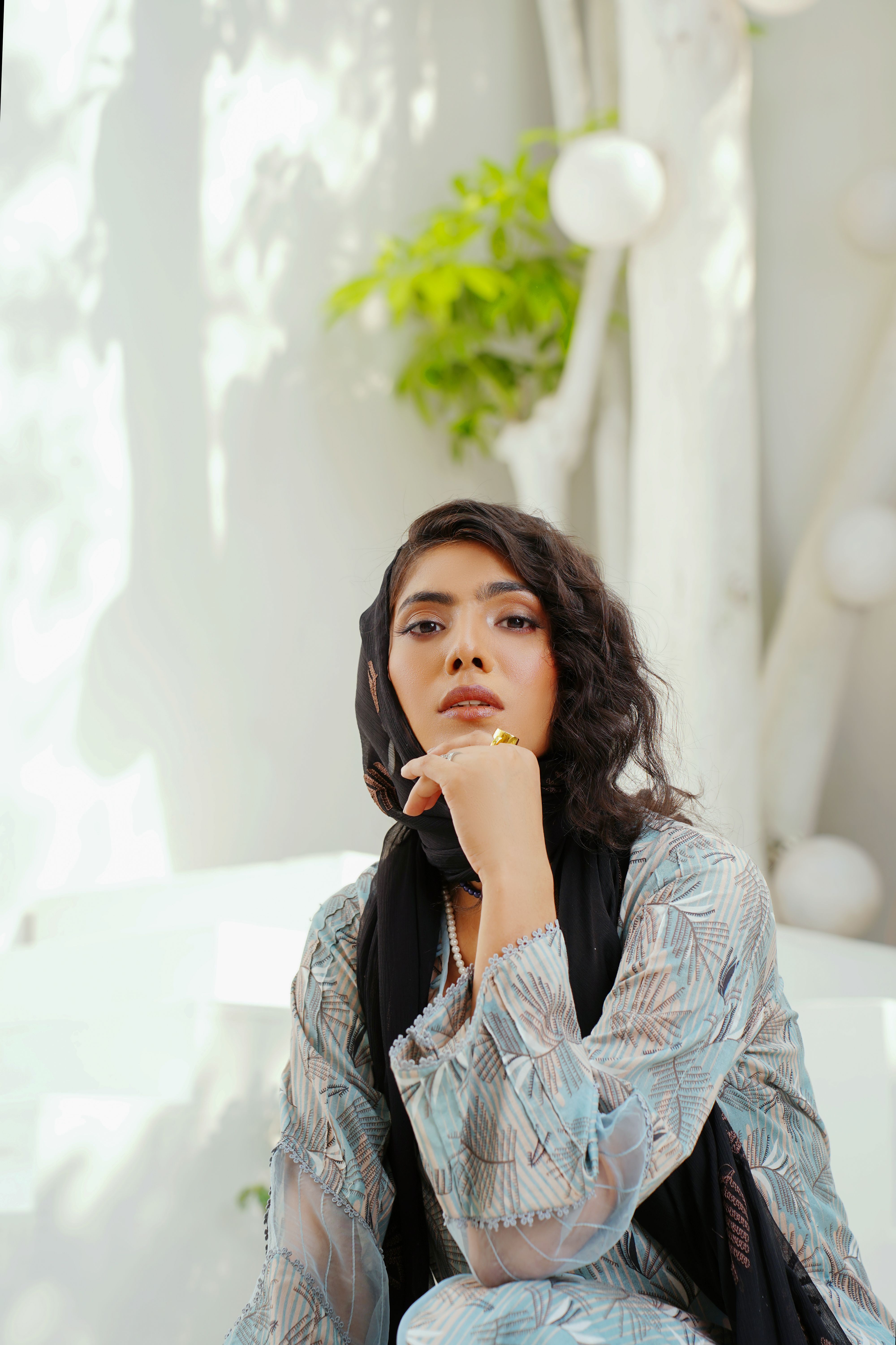 Young woman posing in trendy traditional attire outdoors with a thoughtful look.