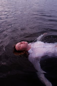 女人平静地漂浮在平静的水面上，营造出一种宁静而内省的氛围