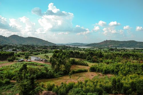 Free A beautiful countryside landscape with lush greenery and distant hills under a blue sky. Stock Photo