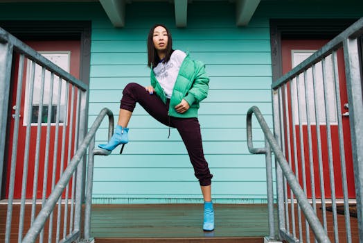 Stylish woman in bright outfit posing on outdoor staircase, showcasing modern street fashion.