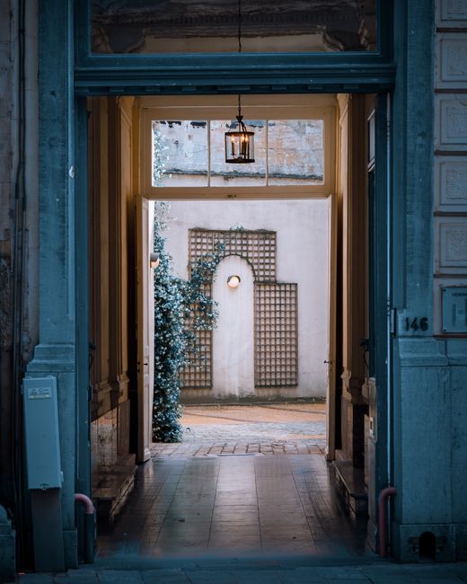 Elegant doorway leading to a charming courtyard in Brussels, showcasing vintage architecture and a tranquil atmosphere.