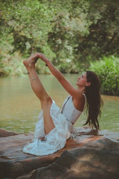 一位身穿白色连衣裙的女子在宁静的河边做瑜伽，享受放松和正念