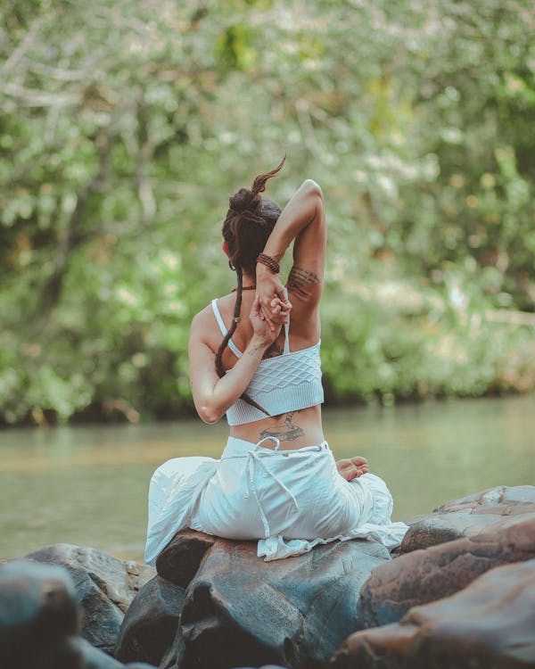 Foto De Vista Posterior De Una Mujer Sentada Cerca Del Cuerpo De Agua Haciendo Yoga