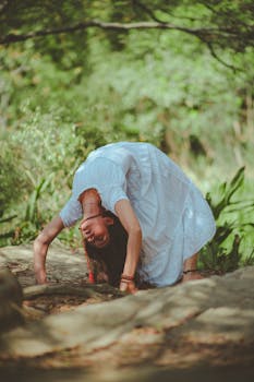 一位身穿白色连衣裙的柔韧女子在风景优美的绿色公园里练习户外瑜伽