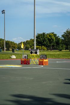 Boomboxes creatively arranged on a basketball court in a sunny park setting, with a natural backdrop.