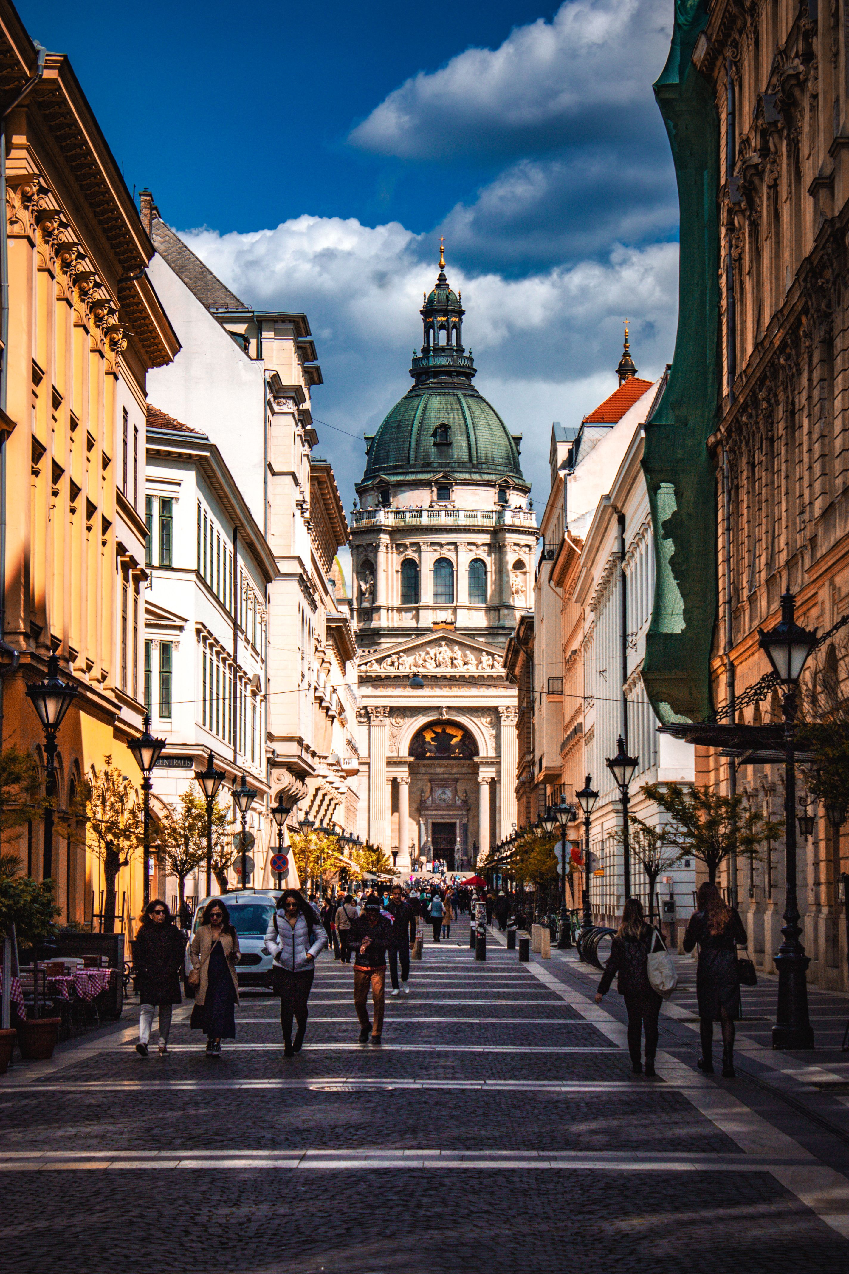 Bustling street view leading to the iconic St. Stephen's Basilica in vibrant Budapest on a sunny day.