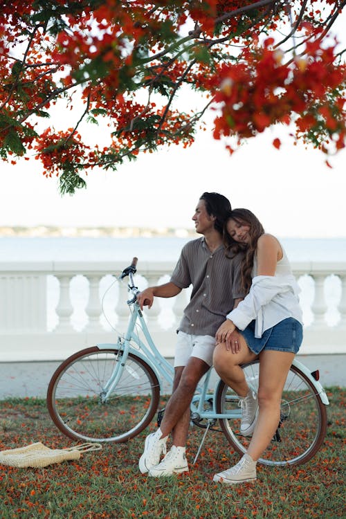 A couple sitting on a bike next to a tree