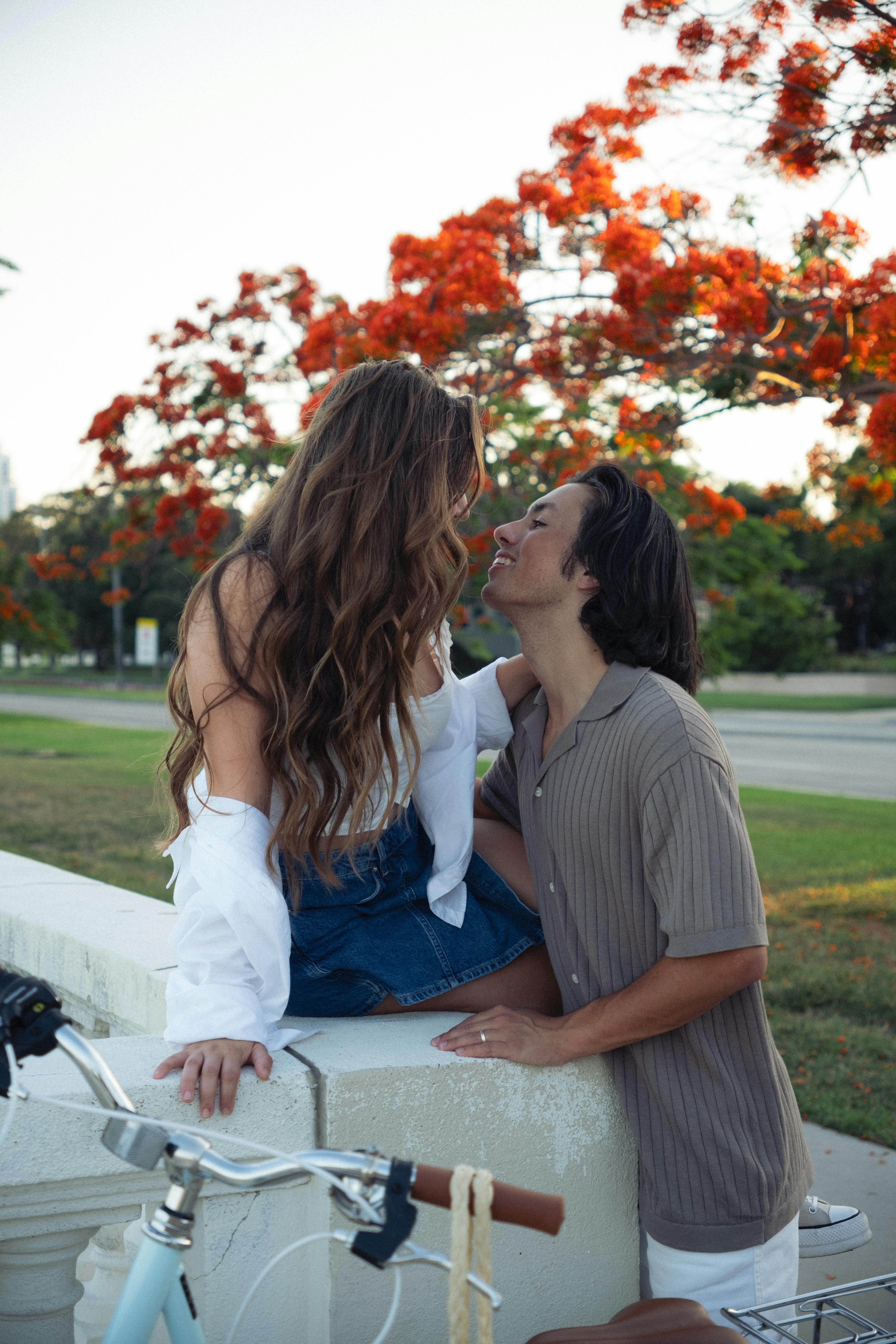 Young couple enjoying a romantic moment outdoors with vibrant autumn foliage in the background.