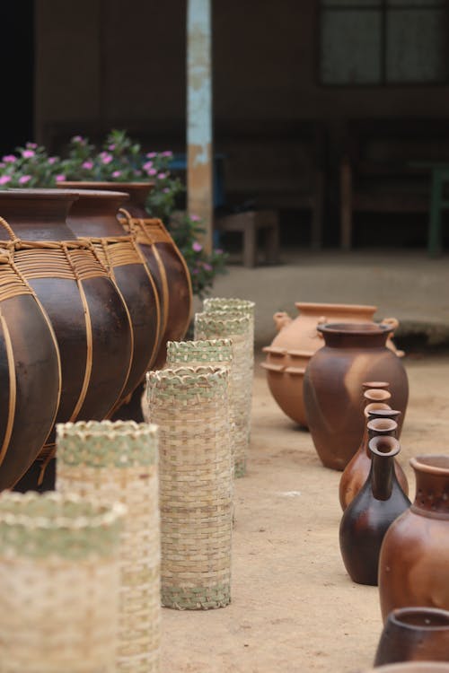 A row of brown pots and baskets on a dirt road