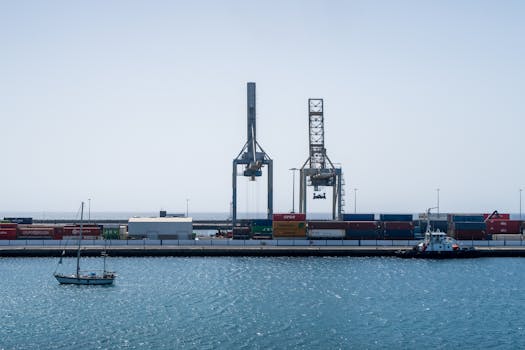 A busy shipping port with cranes, containers, and boats on a sunny day.