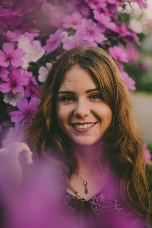 Selective Focus Photo of Woman Near Purple Flowers