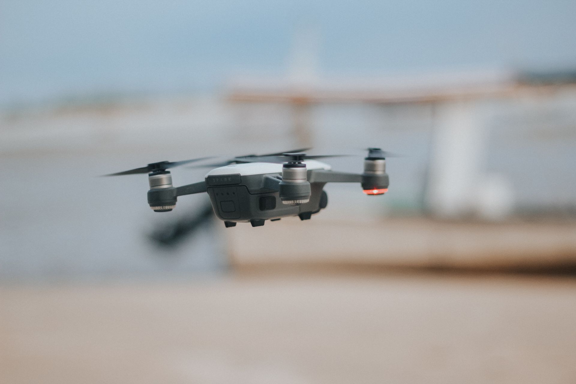 A close-up shot of a drone flying over a sandy beach with the sea in the background, capturing travel and technology themes.