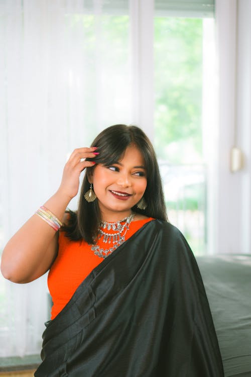 A woman in an orange and black sari posing for a photo