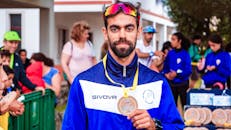 在一场被观众包围的户外体育赛事上，一名留着胡子的男子自豪地展示了他的奖牌