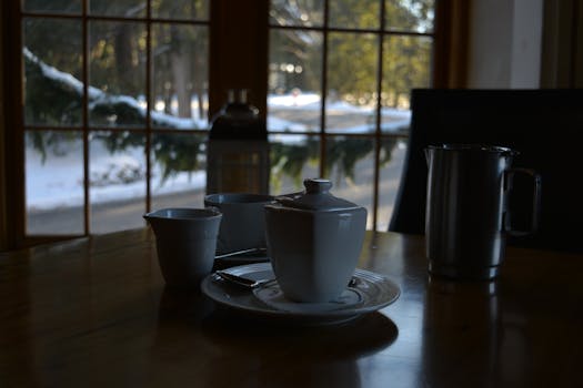 冬日早晨，温暖的阳光洒在餐桌上，茶杯静静摆放，俯瞰着窗外白雪皑皑的大自然