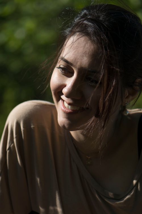 Portrait of a smiling woman in dappled sunlight, photo by Golnar Sabzpoush Rashidi on Pexels