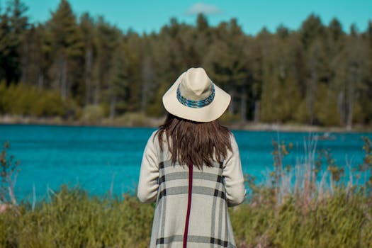 一位女子站在宁静的湖边，四周绿树成荫，享受着大自然的宁静时刻
