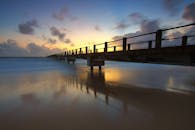 美丽的日落下，码头的倒影映在平静的海面上，营造出宁静的景观