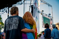 在爱达荷州博伊西市一场充满活力的户外骄傲节上，一对夫妇身披彩虹旗相拥