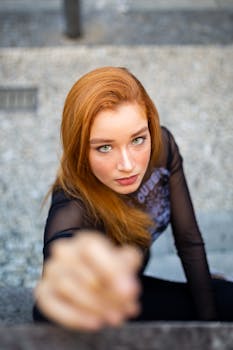 在巴西桑托斯，一位红发女子眼睛明亮，身着黑色上衣，正在户外摆姿势