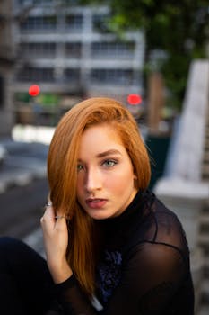 城市环境中，一位红发女子引人注目地坐着，肖像捕捉到她迷人的目光