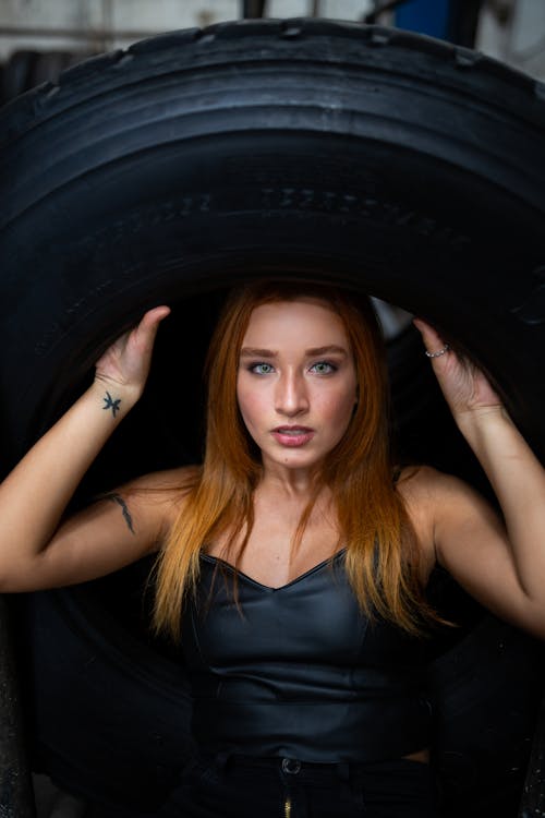 Photo of Woman Carrying Tire Above Her Head