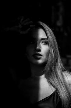 Dramatic monochrome photo of a woman partially in shadow, evoking mystery.