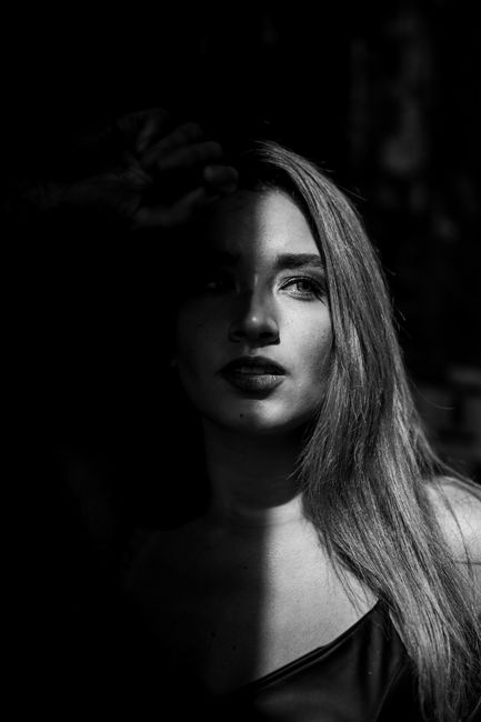 Dramatic monochrome photo of a woman partially in shadow, evoking mystery.