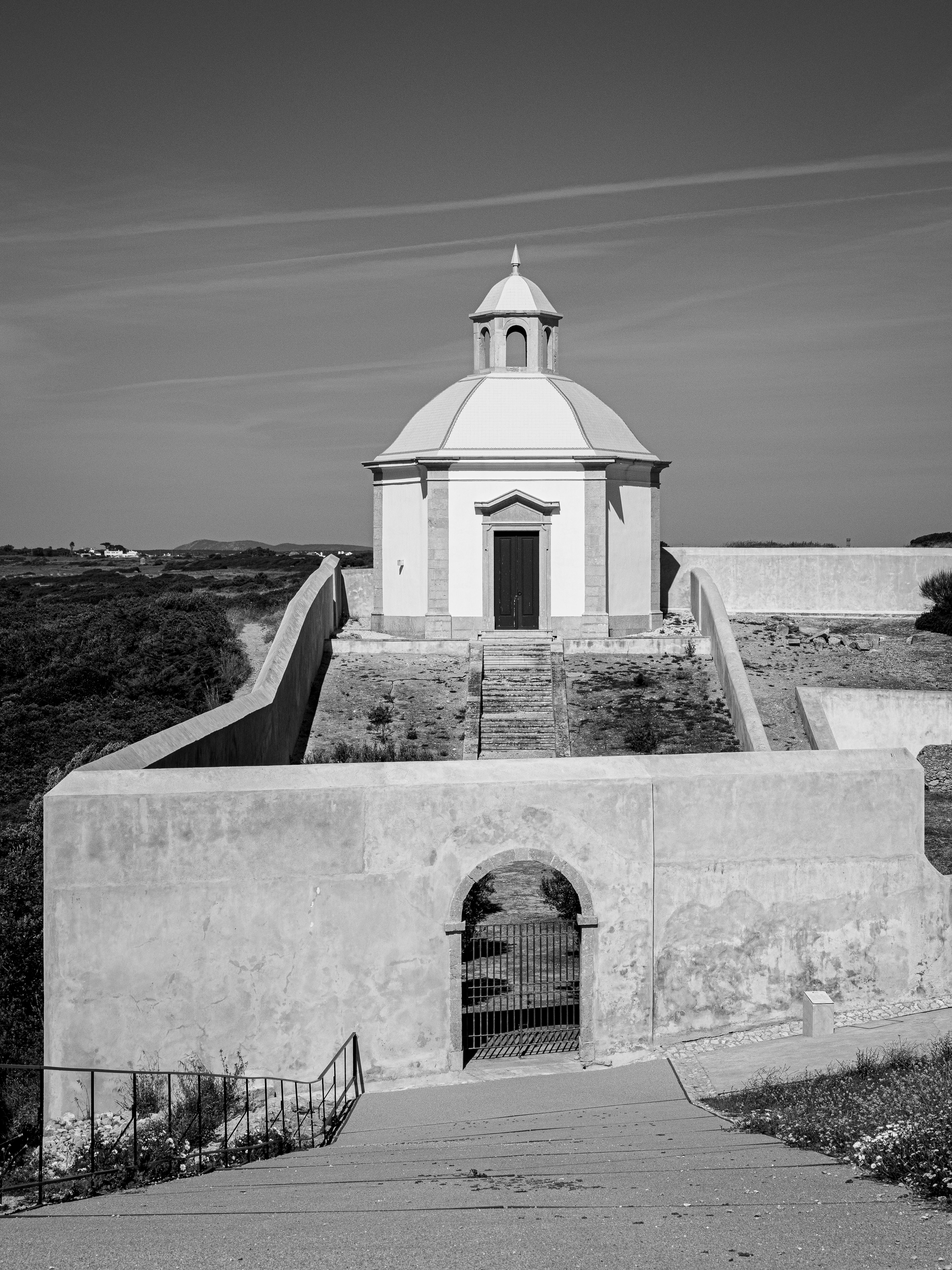 Fotomural Una imagen en blanco y negro de una iglesia rural con cielo despejado, mostrando la belleza arquitectónica.