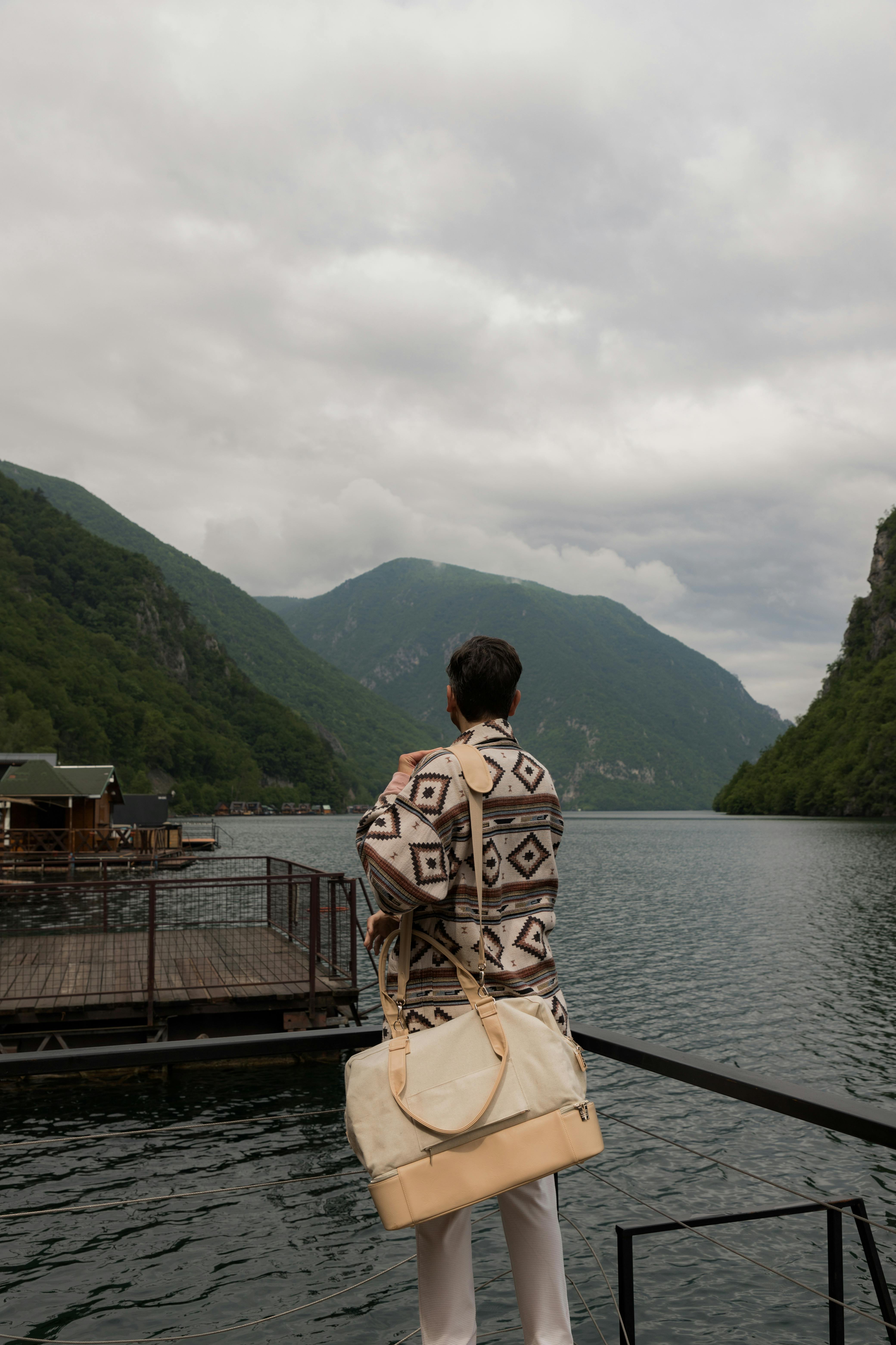 Person enjoying the tranquil view of a lake amidst lush Serbian mountains.