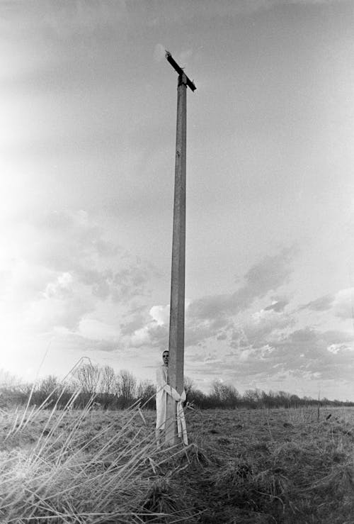 A black and white photo of a pole in the middle of a field