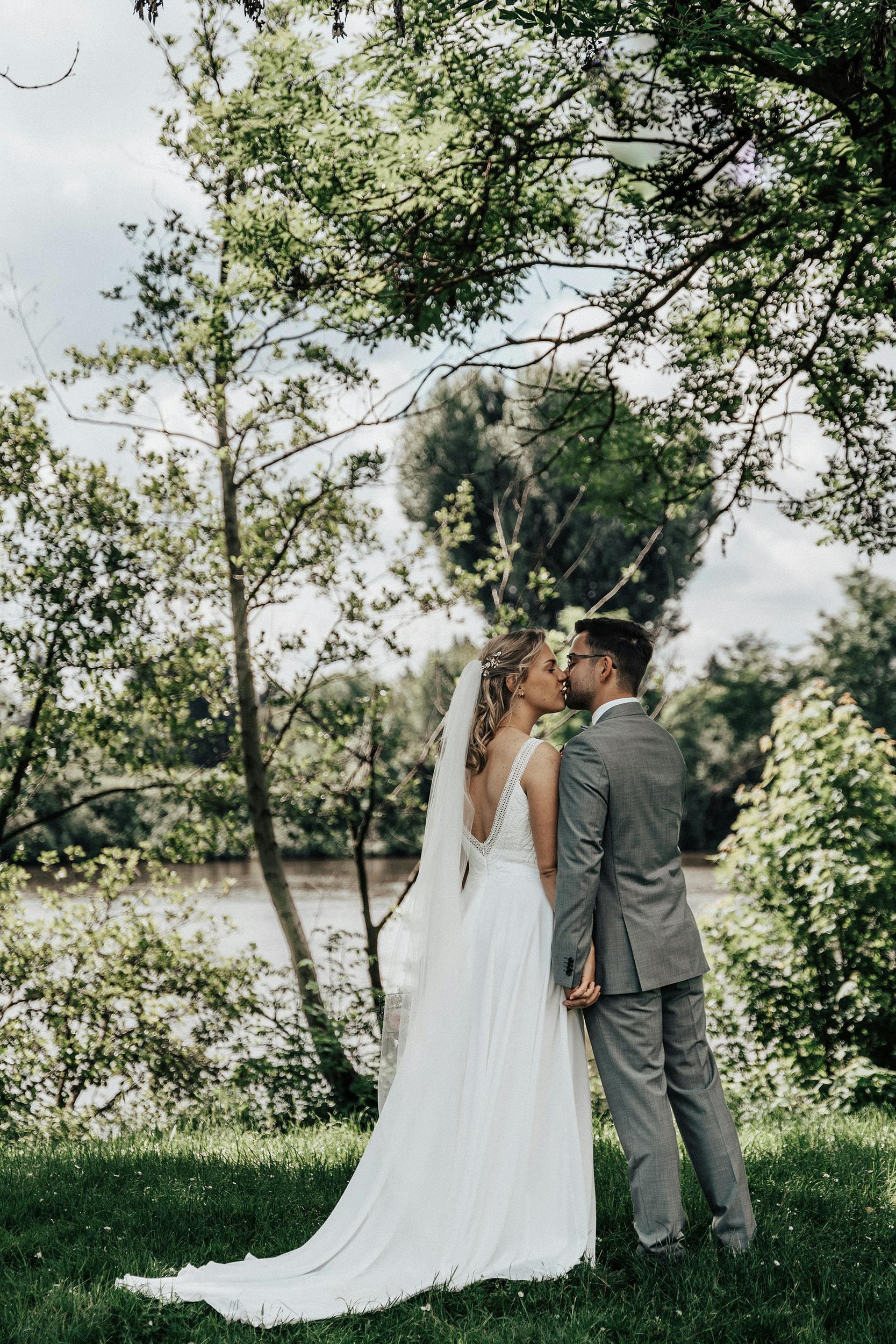 newlyweds kissing on the riverbank