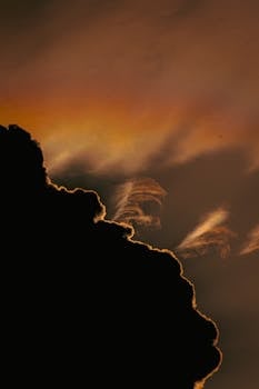 A striking silhouette of clouds against a vivid sunset sky, creating a dramatic cloudscape.
