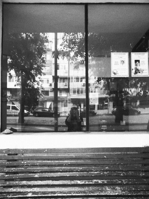Free A monochrome view of city streets reflected in a glass window with visible posters. Stock Photo