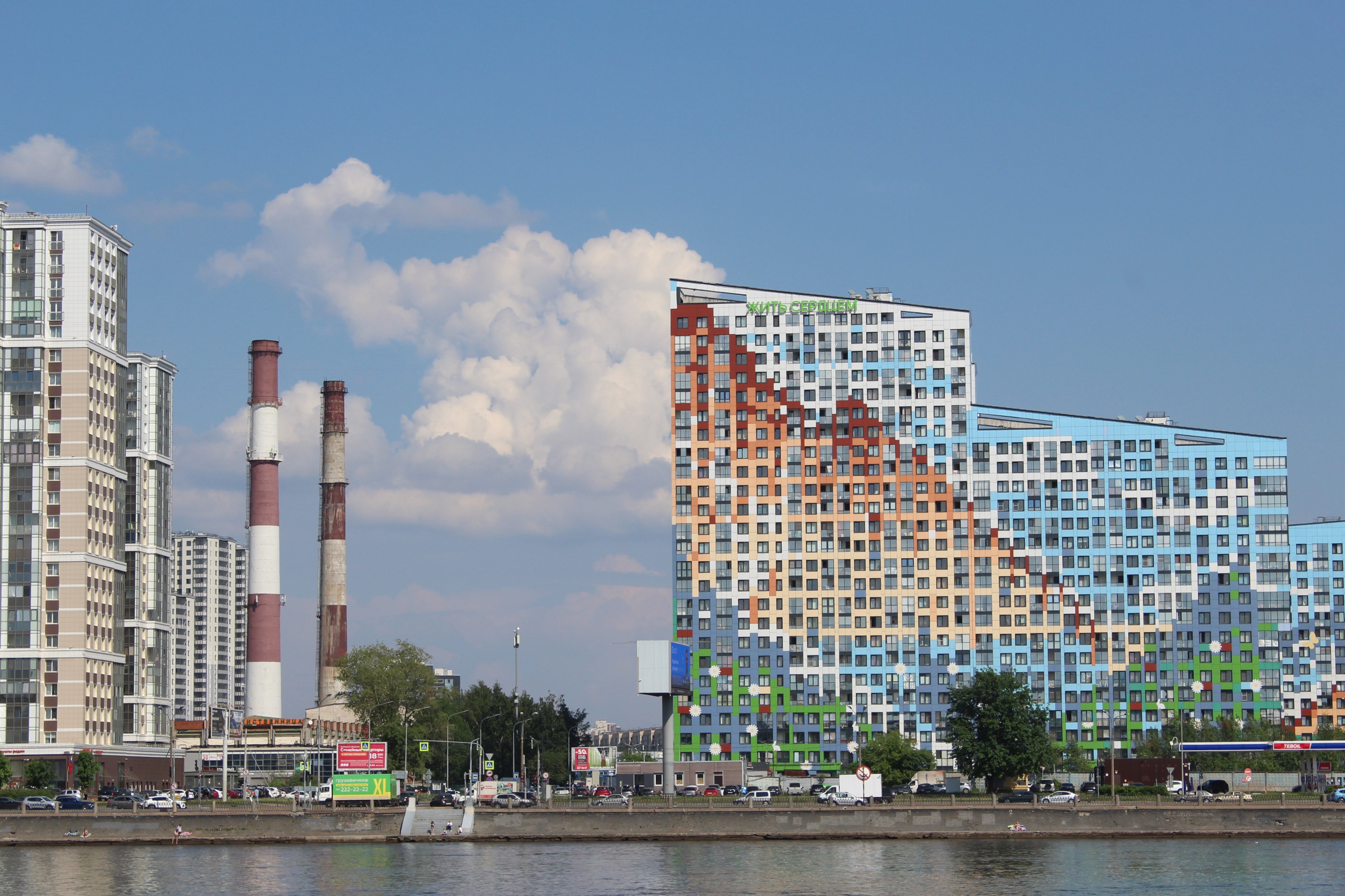 Vibrant cityscape showcasing modern architecture along a riverside with industrial elements.
