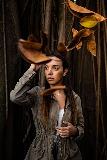 Fashionable woman posing with autumn leaves in São Paulo, embracing the season's beauty.